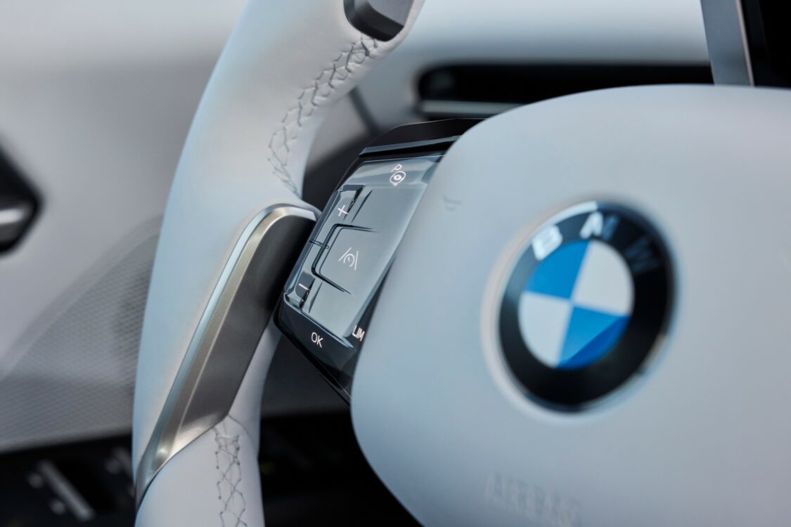 Gros plan sur le volant de la BMW iX3 avec commandes tactiles intégrées et logo BMW au centre