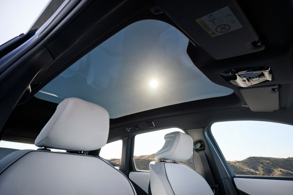 Vue intérieure de la BMW iX3 avec toit panoramique vitré laissant entrer la lumière naturelle.