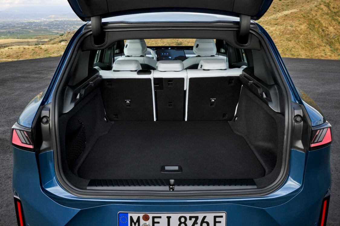 Coffre ouvert de la BMW iX3, montrant un espace de chargement modulable avec les sièges arrière rabattables.