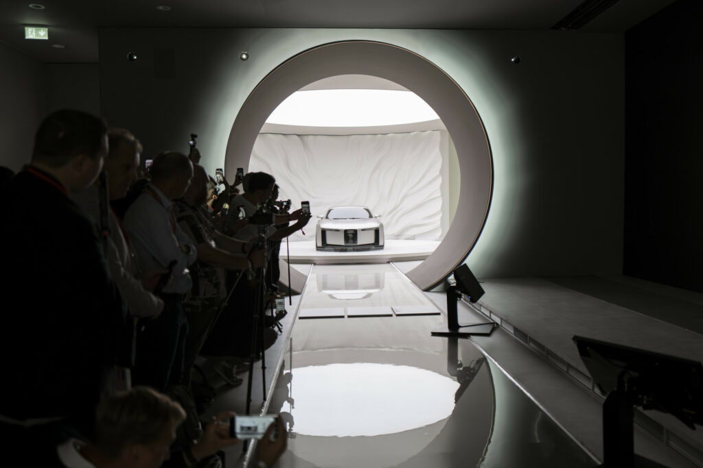 Concept Audi C présenté à l’IAA Mobility, capté de face à travers une arche circulaire, entouré de spectateurs et de photographes.