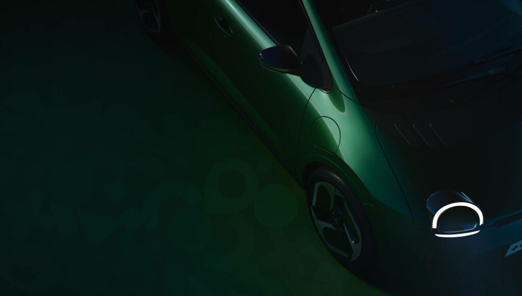 Vue latérale partielle de la Twingo E-Tech electric, lumière rasante sur fond sombre, suggérant une révélation à venir.