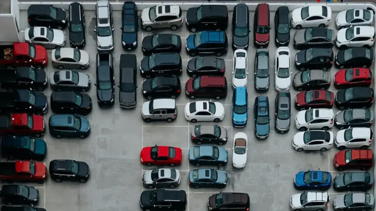 Vue aérienne d’un parking rempli de voitures d’occasion, symbolisant la saturation du marché automobile.